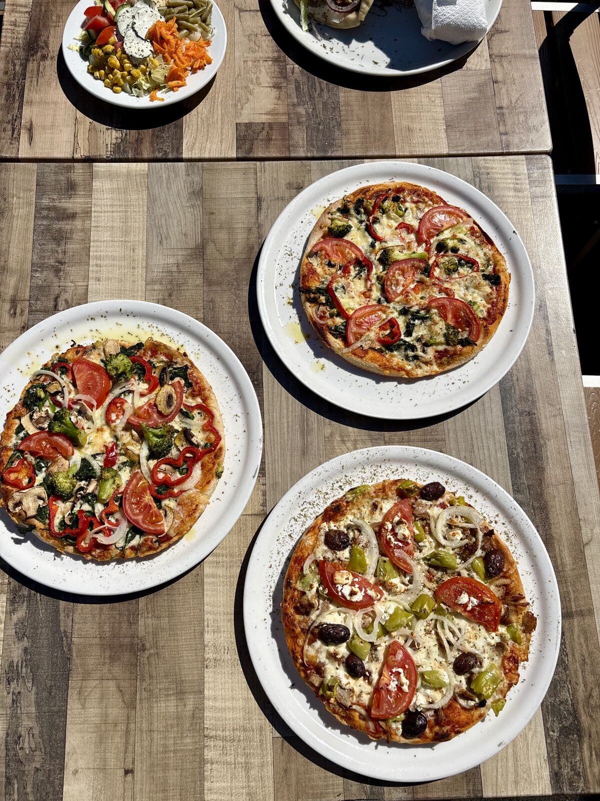 Drei frisch gebackene Pizzen auf der Terrasse